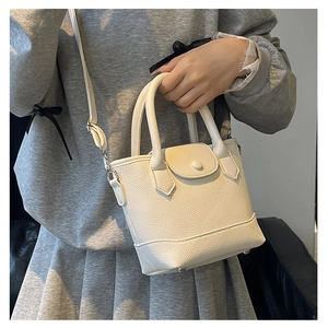 Close-up of beige lychee texture bucket bag with dual handles and adjustable strap