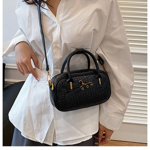 Vue détaillée du sac polochon en cuir tressé noir avec détails dorés sur le mannequin