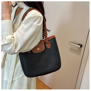 Detailed shoulder view of a black and brown contrast faux leather tote bag with gold logo