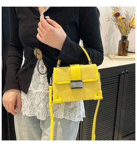 Close-up of vibrant yellow snakeskin pattern handbag with metallic silver lock and trim
