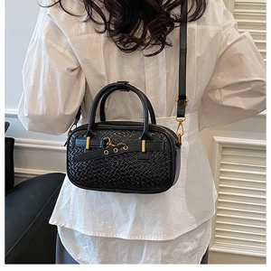 Gros plan d'un sac à main noir tressé avec détails dorés et poignées rondes