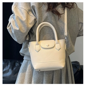 Detail of off-white lychee grain leather bucket bag with top handles and studs