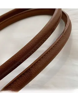 Detail of a brown lychee pattern leather tote bag handle with reinforced stitching