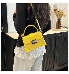 Detail of yellow box bag with python texture, top handle, and silver metal corner guards
