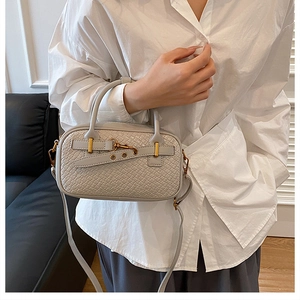 Détail d'un sac à main beige tressé avec garnitures dorées et bandoulière amovible