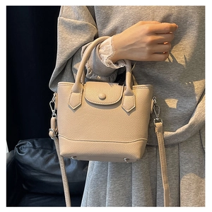 Detail of light khaki leather bucket bag showing grain texture and metal feet