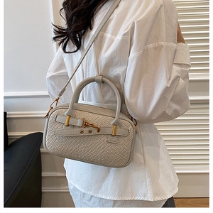 Détail du sac oreiller tressé crème avec fermoir doré et bandoulière amovible élégante
