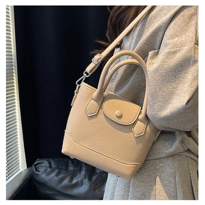 Close-up of beige lychee texture leather mini bucket bag with round flap and dual handles