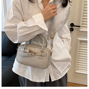 Détail du tissage et des boucles dorées sur un sac bandoulière beige chic