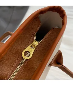 Detailed view of the smooth golden metal zipper and brown lychee grain leather trim