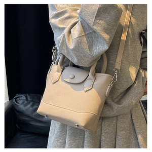 Detail of beige lychee grain leather tote bag with round snap button and metal hardware
