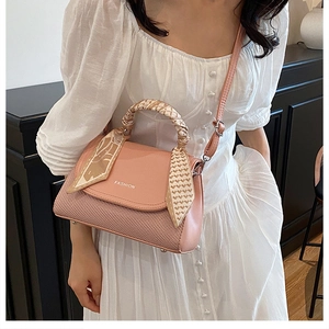 Detail of pink leather handbag with scarf-wrapped handle and fashion lettering