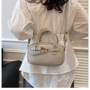 Gros plan d'un petit sac bandoulière tressé porté par un mannequin au style minimaliste