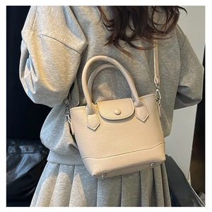 Detail of beige bucket bag with lychee pattern leather and metallic protective feet