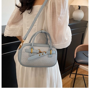 Vue détaillée du sac bowling bleu clair avec texture crocodile et bijoux dorés