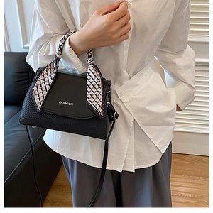 Close-up of black embossed handbag with silk scarf detail and FASHION lettering