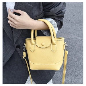 Detail of yellow lychee textured leather crossbody bag with silver buckles and handle