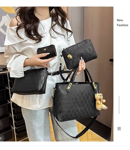 Detail of four-piece black embossed leather handbag set with gold hardware and bear charm