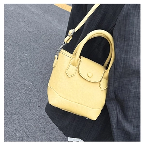 Detail of yellow lychee leather mini bucket bag with silver hardware and shoulder strap