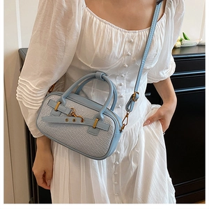 Détail d'un sac à main bleu clair texturé avec boucle dorée et bandoulière réglable