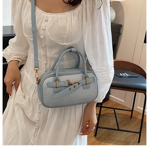 Détail de la texture tissée bleu clair et boucle dorée sur un sac à main en similicuir
