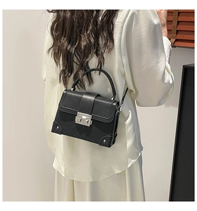 Rear view of a model wearing a black woven texture box bag with silver metal lock