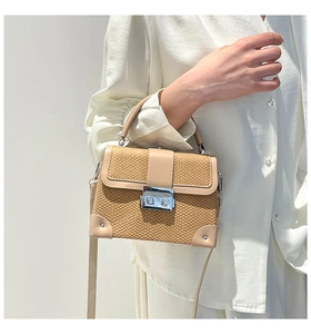 Detail of light brown woven texture handbag with silver metallic lock and handle
