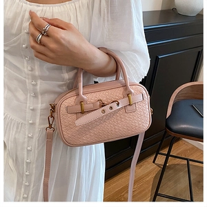 Détail du sac à main rose clair à texture tissée avec boucle et garnitures dorées