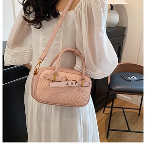 Détail du sac à main en cuir tressé rose pâle montrant les boucles dorées et le grain