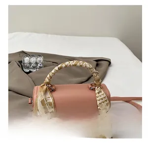 Detail of pink crossbody bag featuring woven texture and decorative printed silk scarf