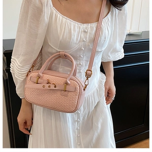 Détail de la texture tressée et de la sangle en cuir à œillets du sac rose