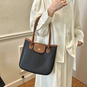 Elegant two-tone tote bag with black body and brown handles featuring gold buckle detail