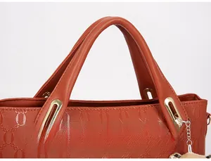 Macro detail of tan faux leather handbag handle with gold metal hardware and chain embossing