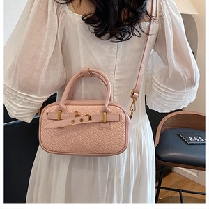 Détail du sac bandoulière rose tissé avec garnitures dorées et boucle sur un modèle