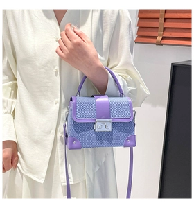 Detail of purple woven texture bag with silver hardware and leather trim on white background