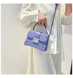 Detail of purple faux snakeskin crossbody bag featuring silver hardware and top handle