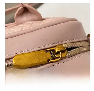 Détail du zip doré vintage et de la texture en cuir tressé du sac bowling rose