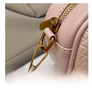 Détail du crochet doré et de la texture en cuir tressé sur le sac bowling rose