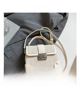 Detail of cream-colored woven texture handbag with vintage metal lock and corner guards