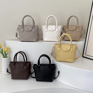 Minimalist soft leather tote bags in six colors displayed on a modern white stand