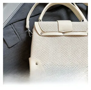 Close-up of cream white handbag with woven pattern texture and silver rivet details