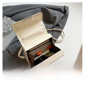 Interior view of the cream box bag showing capacity for a smartphone and lipstick
