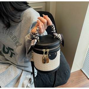 Detail of color-block bucket bag with woven base, silk scarf handle, and gold lock charms