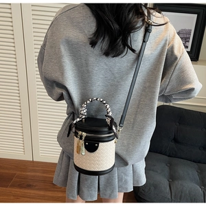 Detail of black and white woven bucket bag with patterned scarf handle and shoulder strap