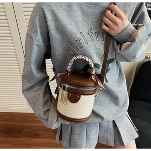 Detail of contrast color bucket bag with woven texture and scarf-wrapped top handle strap