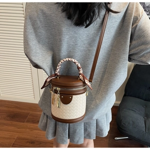 Detail of woven bucket bag with silk scarf handle and leather strap on a model