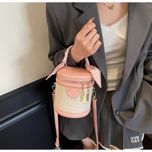 Detail of contrast bucket bag with woven texture, silk scarf handle, and gold hardware