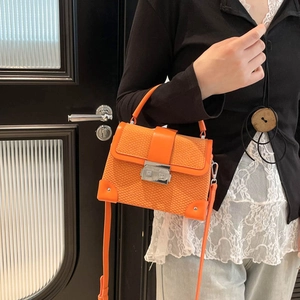 Orange woven texture box bag with metal corners and silver lock, worn by a model