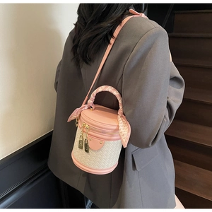 Detail of pink woven bucket bag with decorative silk scarf handle on model's shoulder