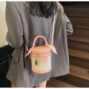 Detail of pink woven bucket bag with silk scarf on handle worn by model on stairs